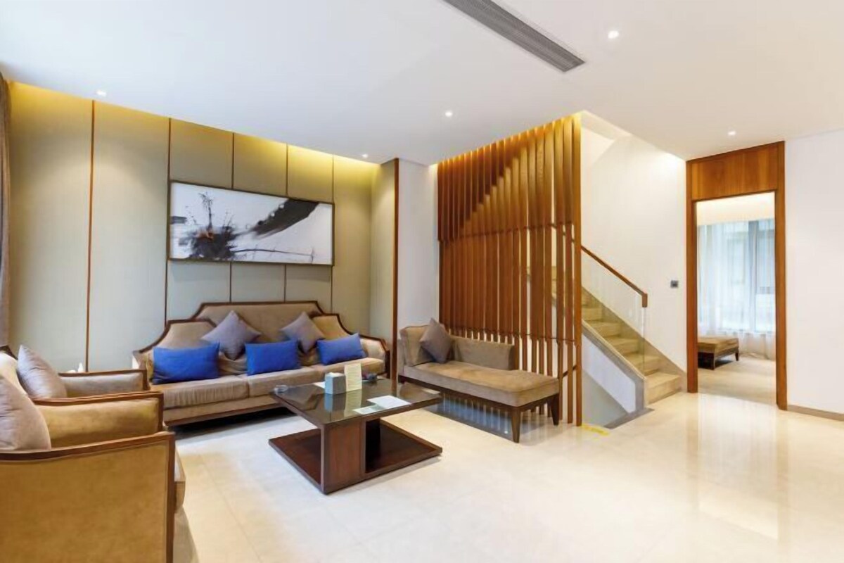 A modern living room with a sofa, coffee table, and a staircase.