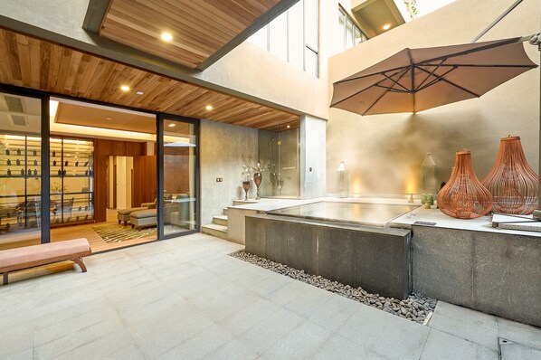 Un intérieur moderne avec un mur en verre, un espace salon et un grand parasol.