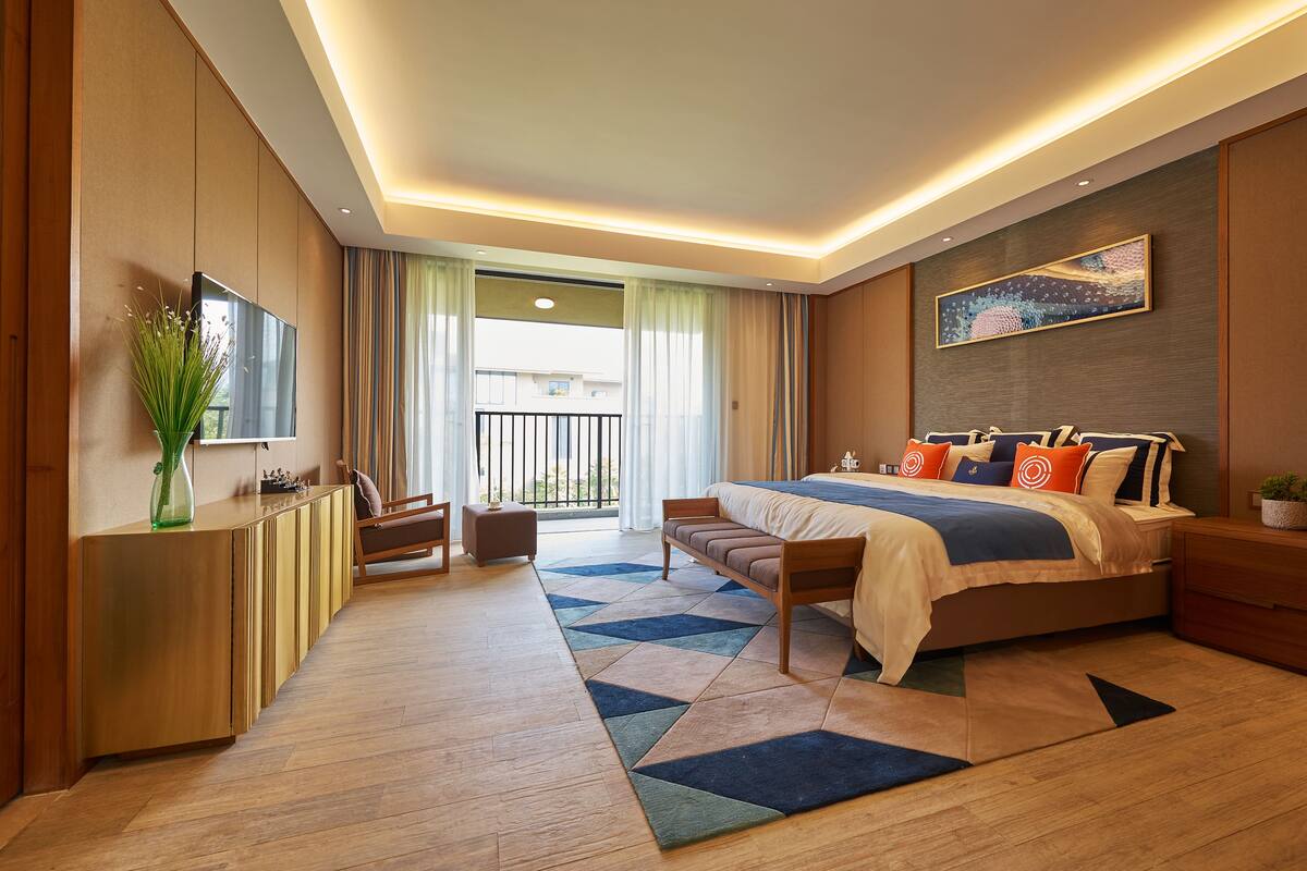 Quarto de hotel moderno com uma cama grande, uma mesa de trabalho e vista para o exterior.