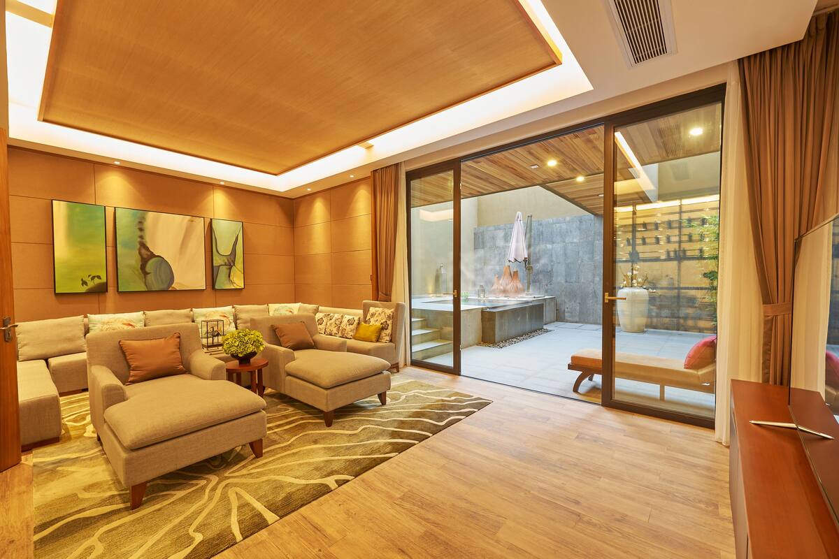 Uma sala de estar moderna com um conjunto de sofás, uma mesa de centro e uma janela grande com vista para uma área de spa.