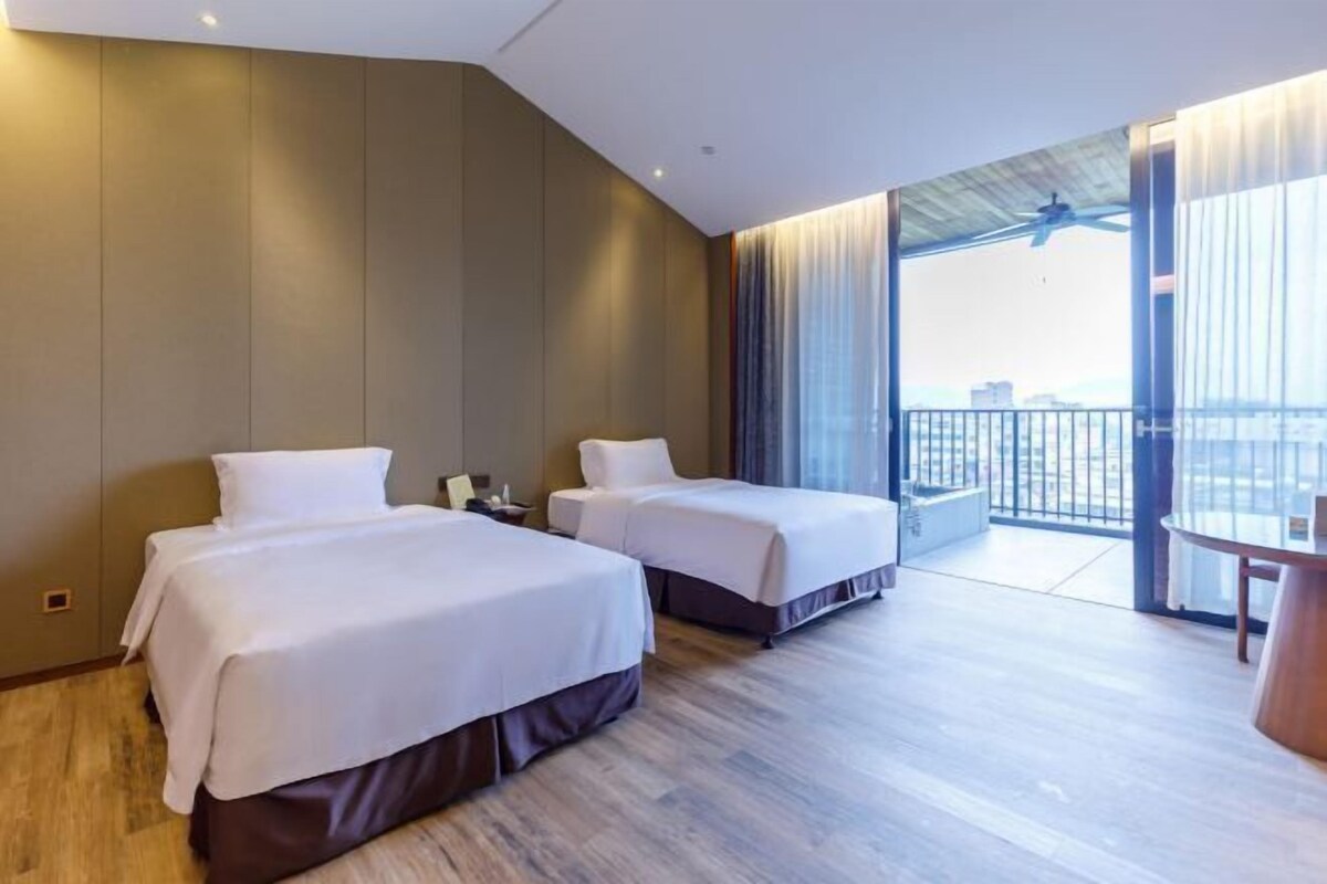 A hotel room with two beds, a balcony with a view, and a round table.