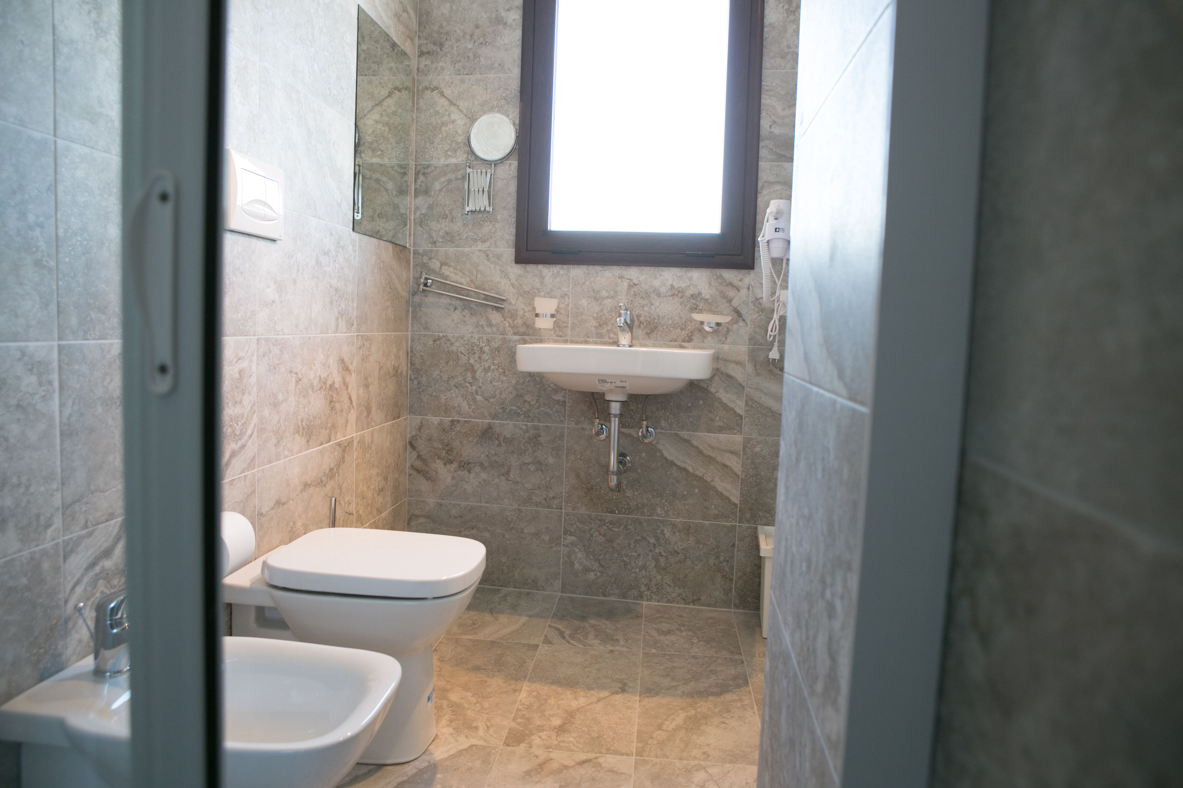 Un baño con inodoro, bidé, lavamanos y espejo.