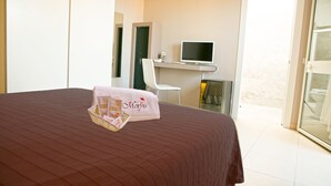A hotel room with a large bed, a desk with a computer, a chair, and a window with a view. - Morfeo Luxury Rooms (Pozzallo)