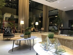 A modern lounge area with a round table, chairs, and potted plants. - Avior Hotel (General Santos)