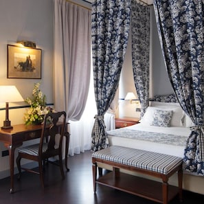Ein Hotelzimmer mit einem Bett, einem Schreibtisch, einem Sessel, einem Nachttisch und einer Lampe.