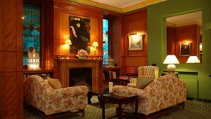 A room with two floral-patterned sofas, a small table, and a fireplace.