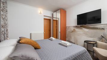 A modern bedroom with a bed, a TV mounted on the wall, a chair, and a small table.