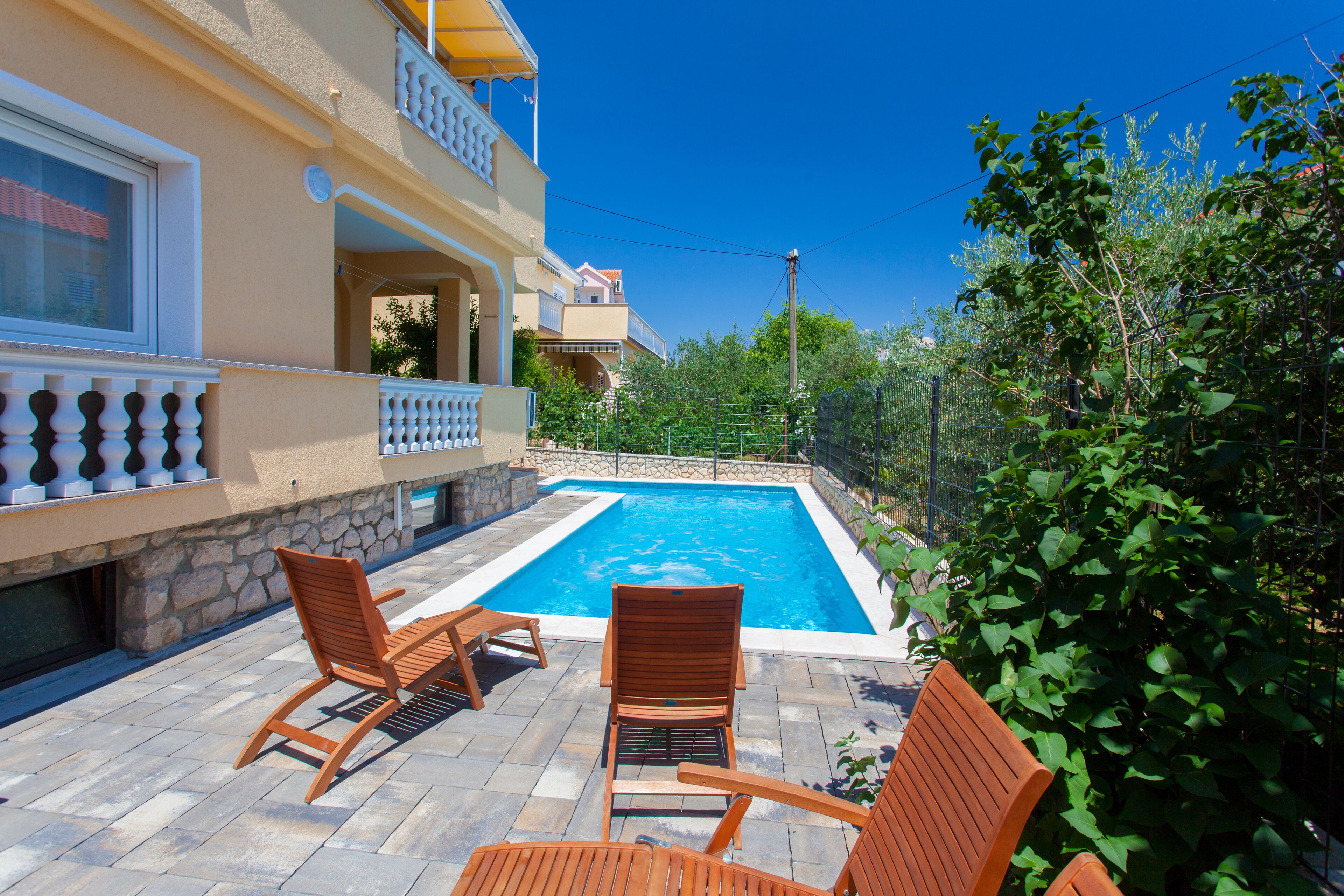 A poolside area with two wooden chairs and a stone wall.
