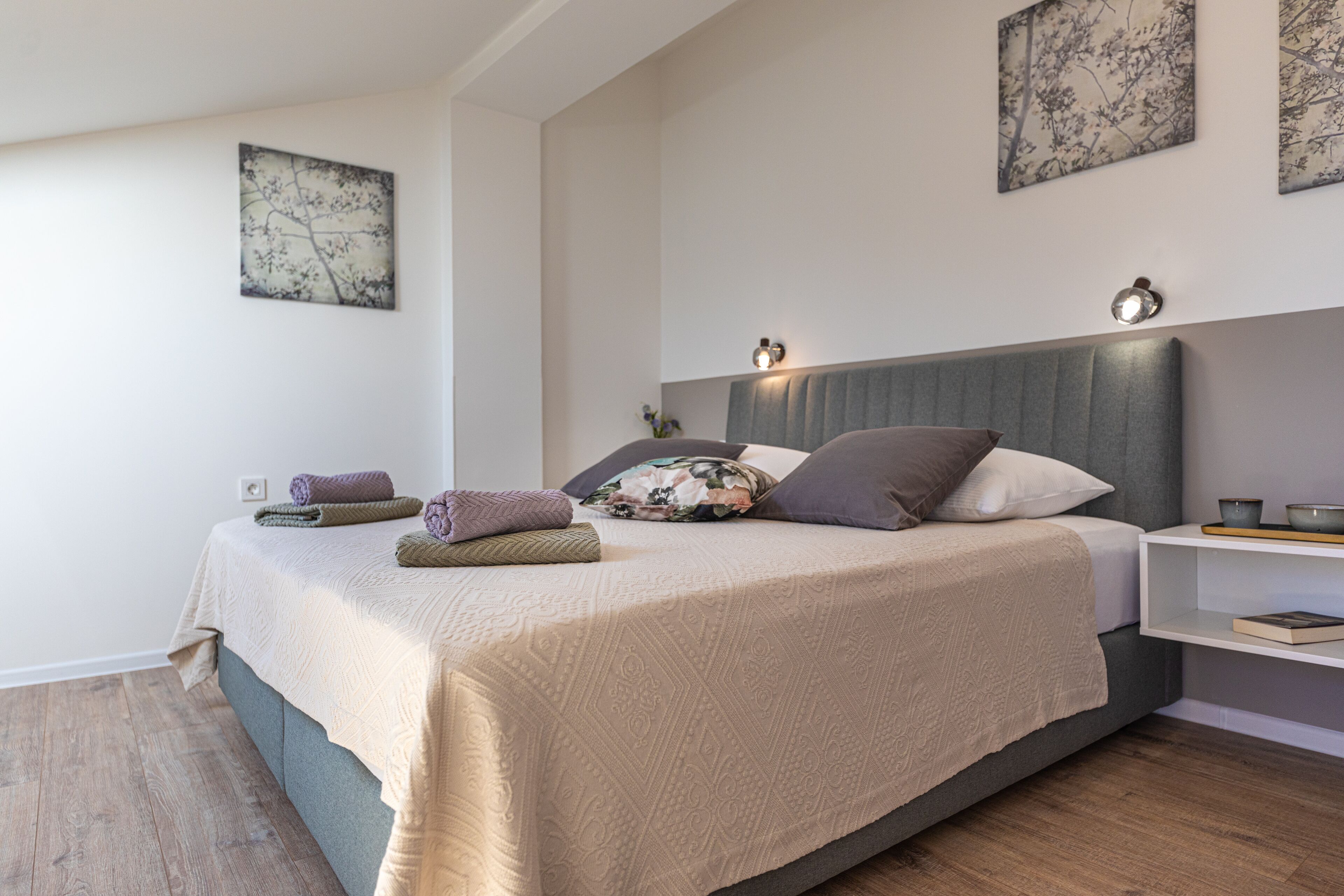 Un dormitorio moderno con una cama grande, una mesita de noche y obras de arte en la pared.