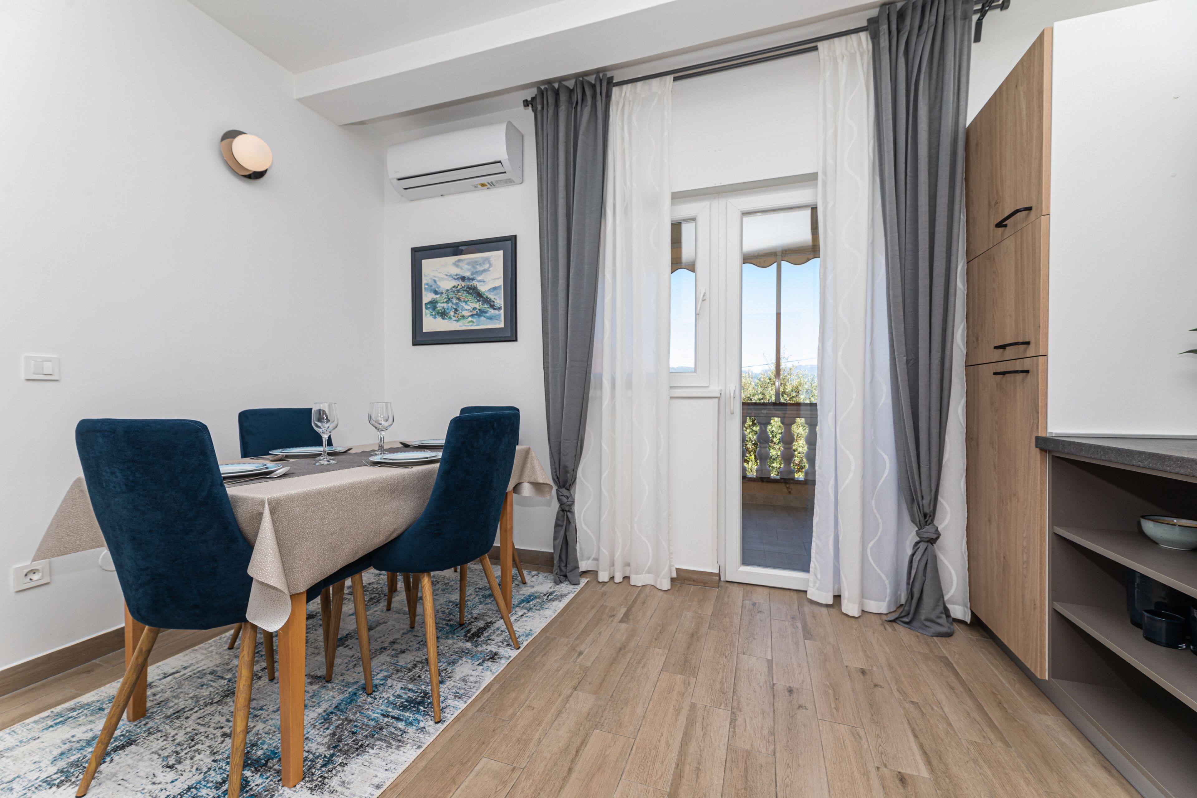 A dining area with a table set for four, blue chairs, and a wooden floor.