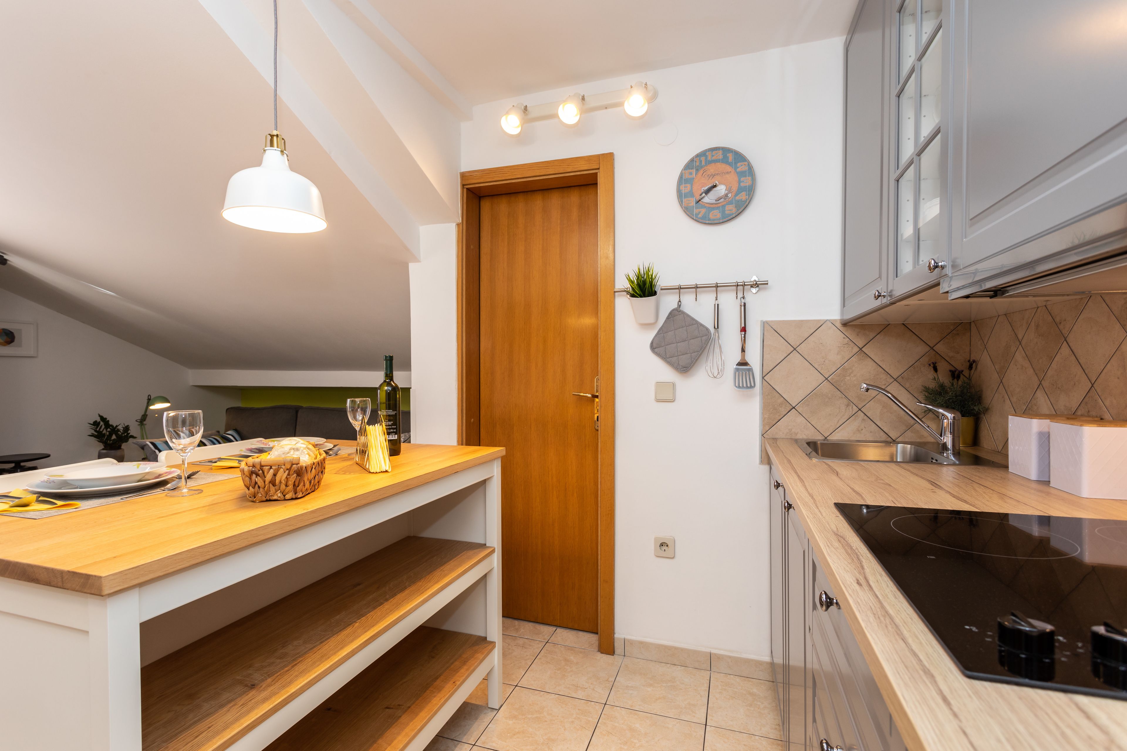 A modern kitchen with a wooden countertop, a built-in oven, and a hanging light fixture.