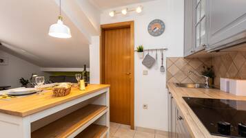 A modern kitchen with a wooden countertop, a built-in oven, and a hanging light fixture.