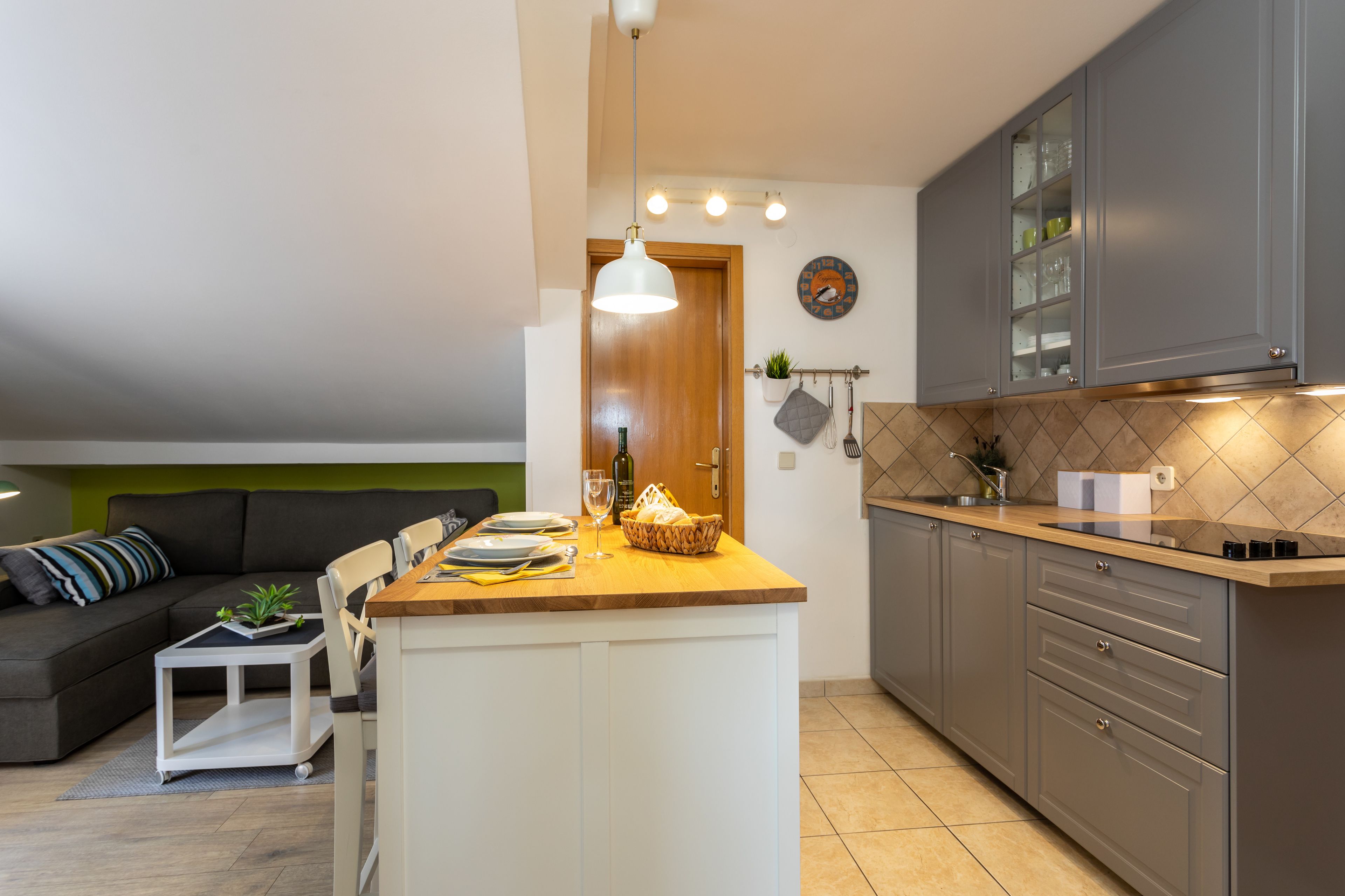 A compact kitchen with a central island, grey cabinets, and a wooden countertop.