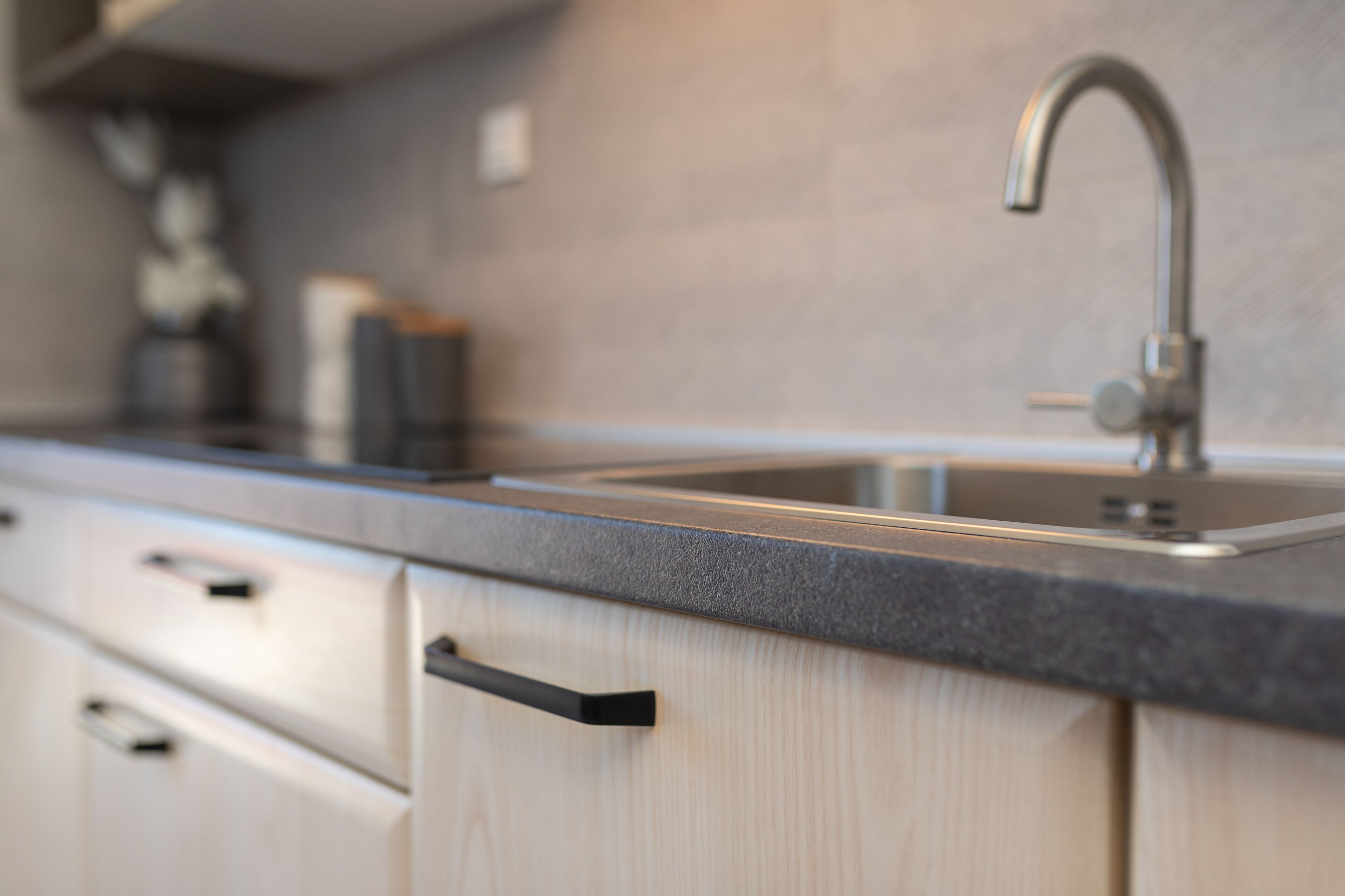 Une cuisine dotée d’un évier moderne en acier inoxydable, de meubles en bois et d’un plan de travail en granit.