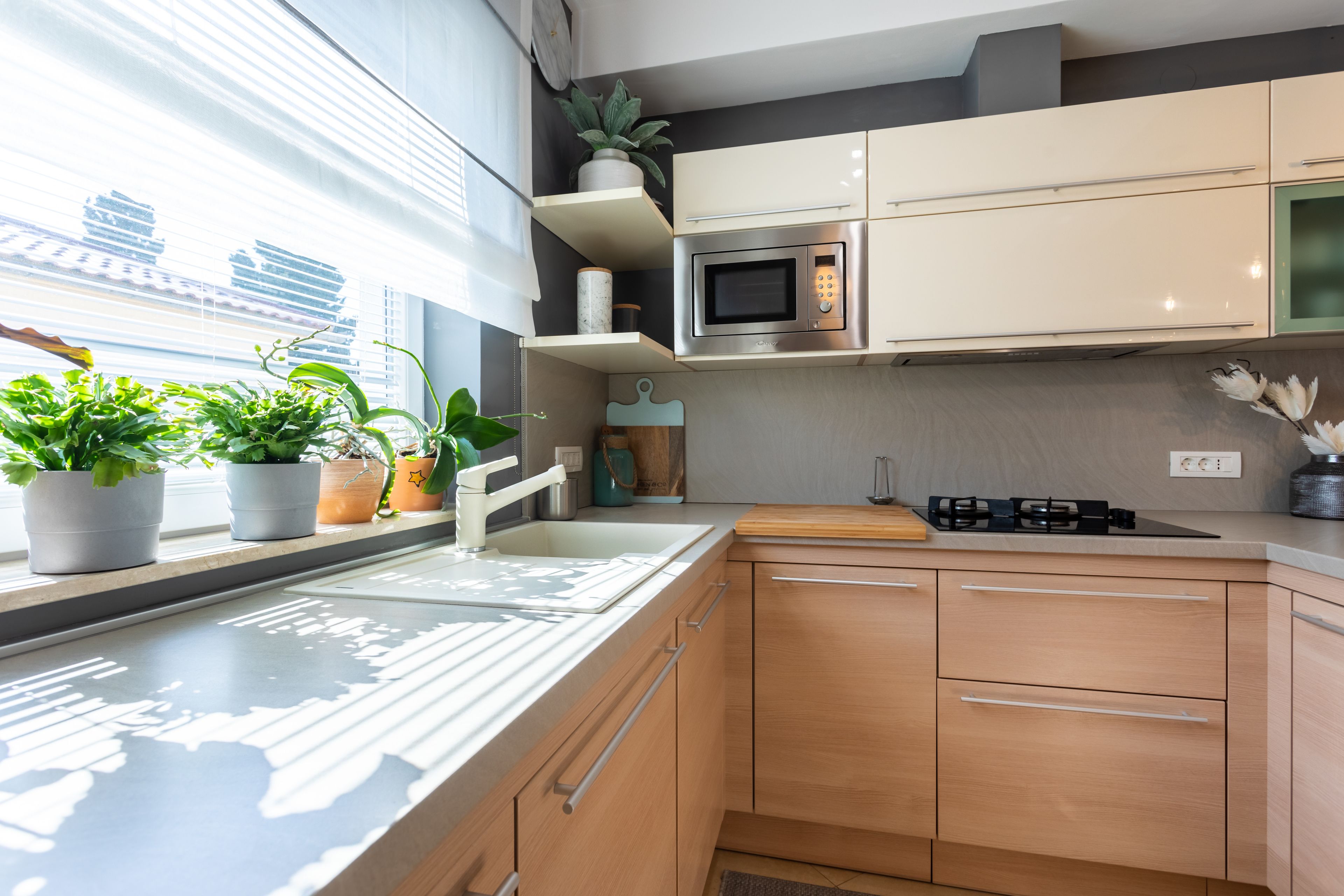 Una cocina moderna con microondas integrado, un lavamanos y armarios de madera.