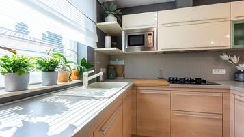 Una cocina moderna con microondas integrado, un lavamanos y armarios de madera.