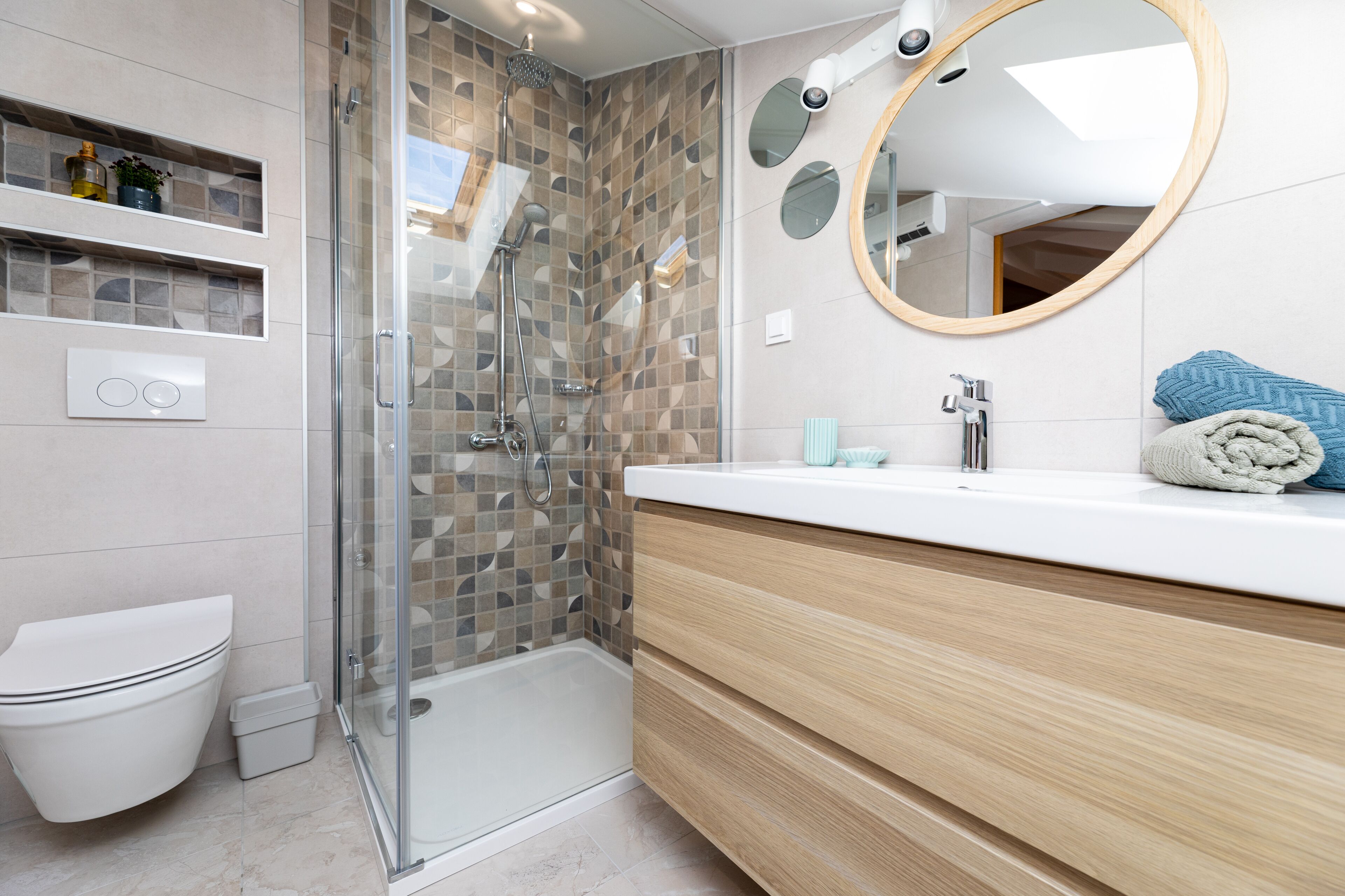 A modern bathroom with a glass-enclosed shower, a white toilet, a vanity with a mirror, and a towel rack.