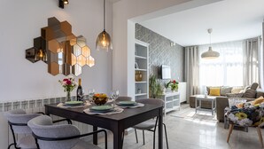 Un comedor moderno con una mesa de madera oscura, sillas tapizadas en gris y un espejo hexagonal en la pared.