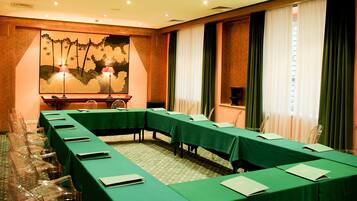 A conference room with a long table, clear chairs, and a large painting on the wall.