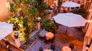 Ein Terrassenbereich im Freien mit Tischen und Stühlen, umgeben von Pflanzen und Blumen.