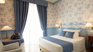 Un dormitori amb llit, dues làmpades de nit, una tauleta de nit, una cadira i una finestra amb cortines.