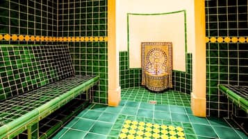 Una habitación con paredes y suelo de azulejos verdes, un banco y un panel decorativo.