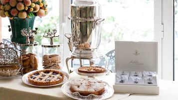 Una mesa con diferentes alimentos, incluyendo tartas y pasteles, además de una máquina de café.