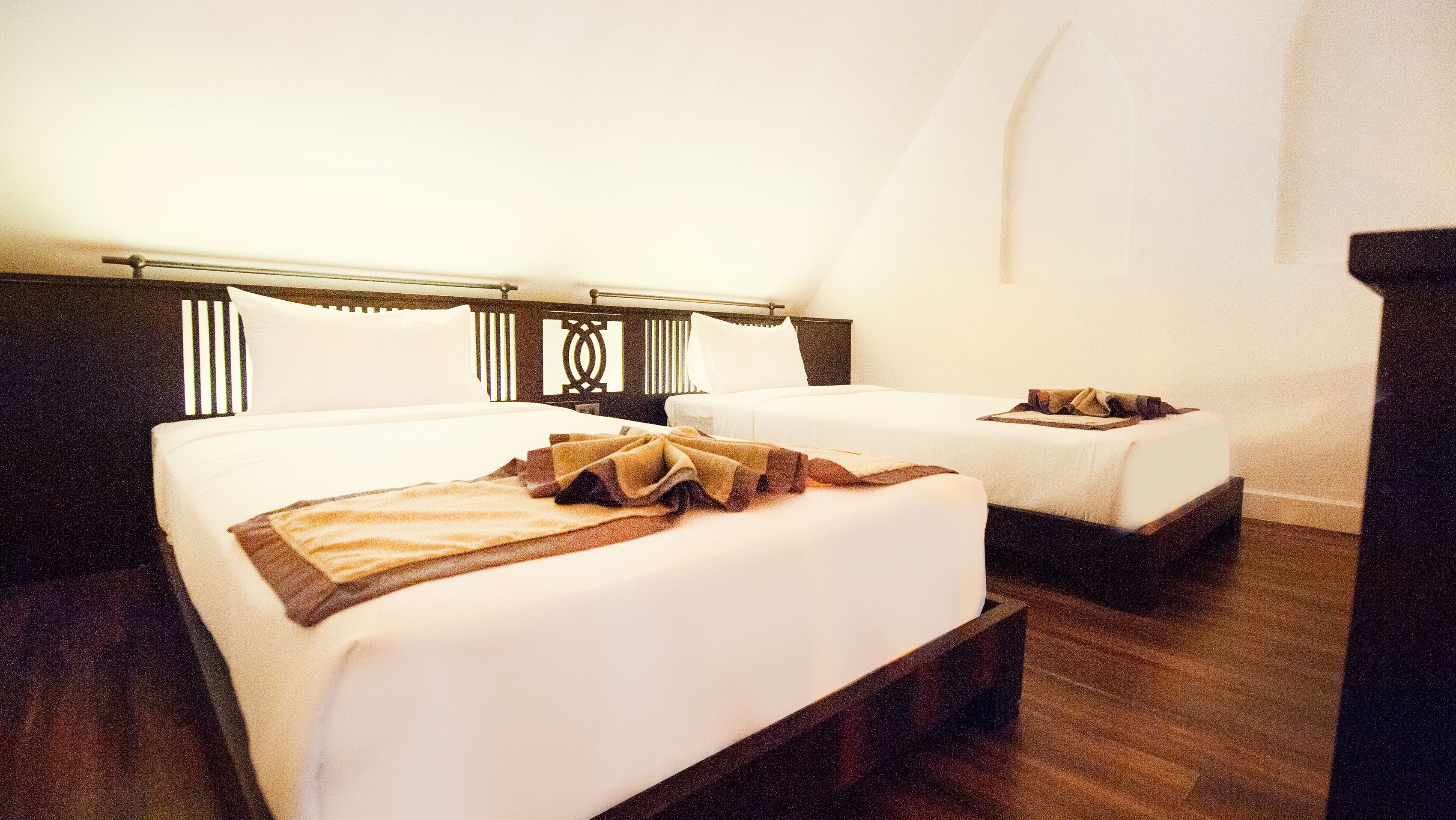 Habitación de hotel con dos camas, cabeceros de madera y un ventanal grande.