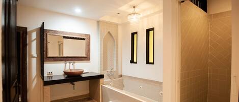A bathroom with a large mirror, a vessel sink, a freestanding bathtub, and a shower area.