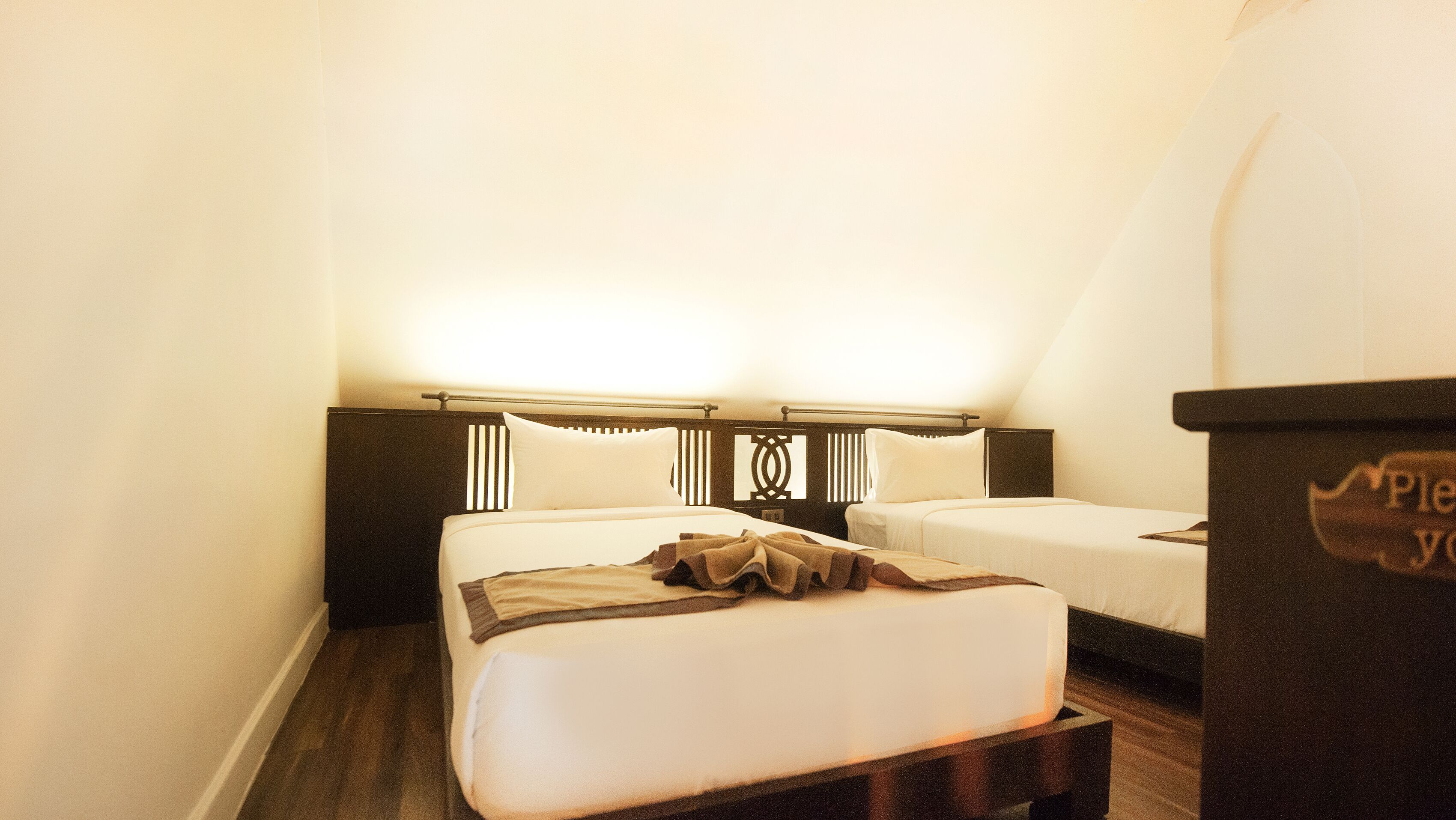 Ein Hotelzimmer mit zwei Betten, einem Holzkopfende und einem Nachttisch mit einem Schild.