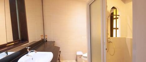 Une salle de bain moderne avec un grand miroir, un lavabo blanc, des toilettes et un espace douche.