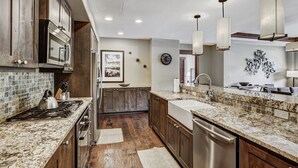 A modern kitchen with granite countertops, stainless steel appliances, and wooden cabinets.