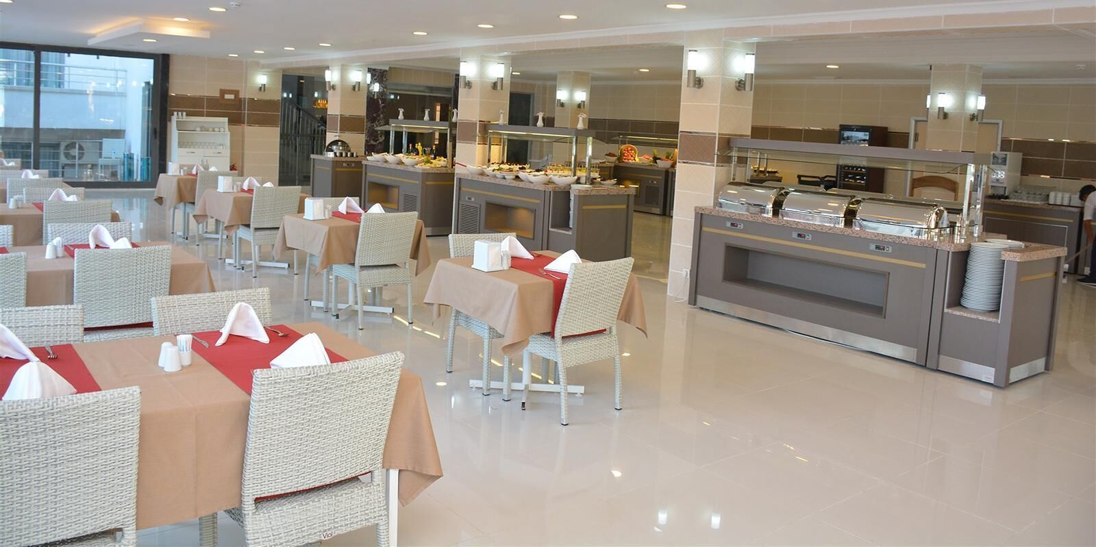 A modern restaurant with wicker chairs and tables, a buffet area, and a view of the city.