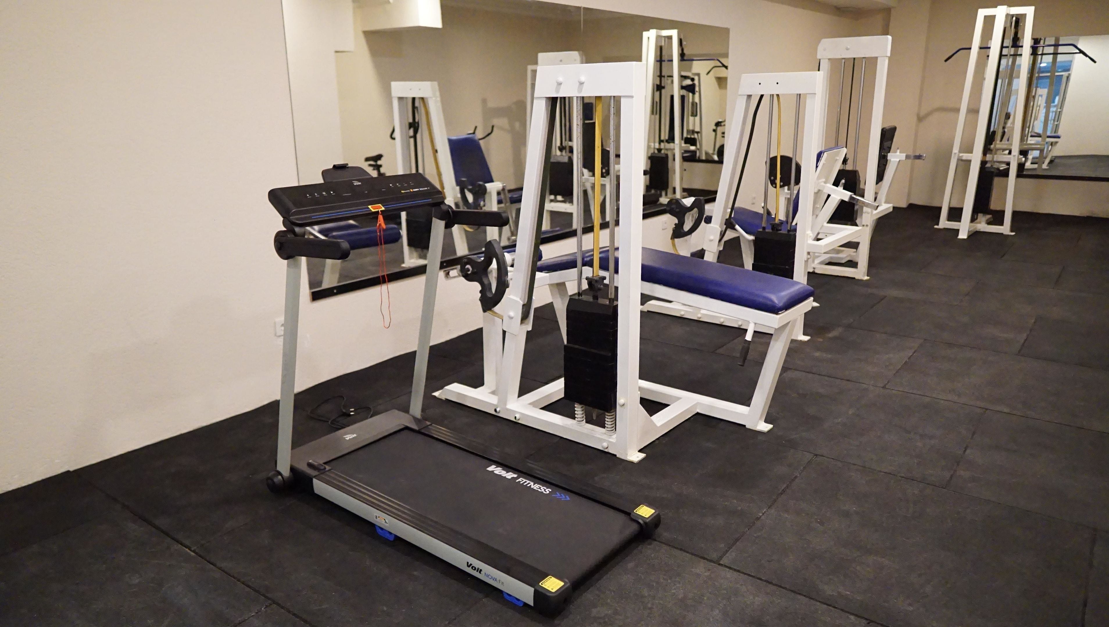 A gym with treadmills, weight machines, and benches.
