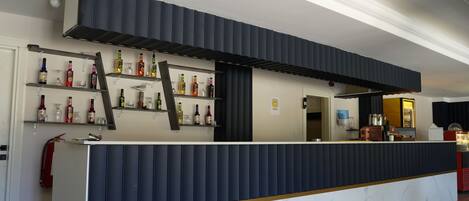 A bar area with a marble countertop and shelves of liquor bottles.
