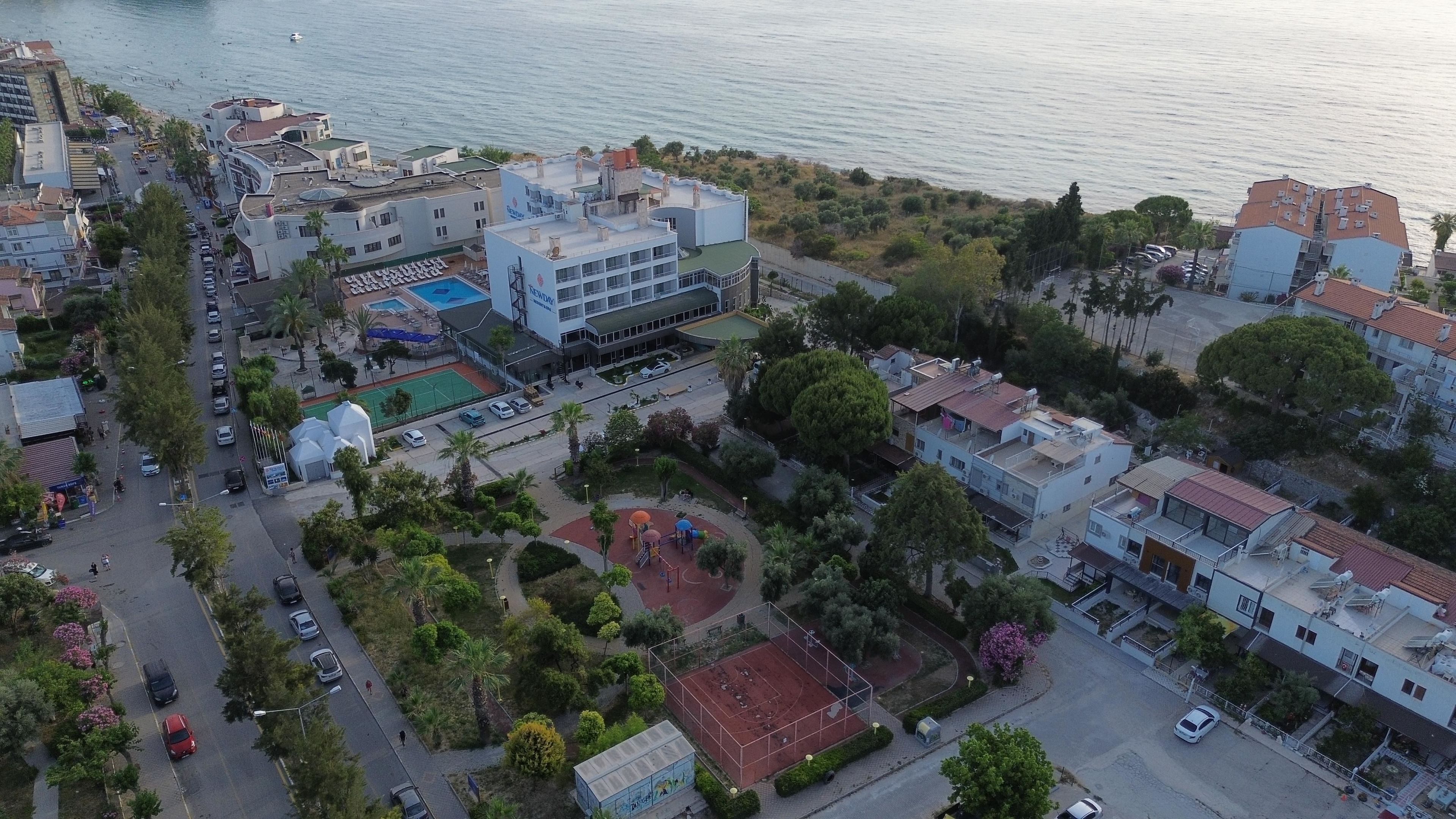 Vista aérea de uma área urbana costeira com edifícios, uma praia e um parquinho.
