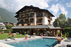 A hotel with a pool, outdoor seating, and mountain views. - Hotel L'Oustalet (Chamonix-Mont-Blanc)
