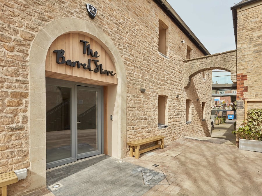 Un edificio de piedra con un letrero de madera que dice "The Barrel House".