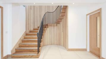 A modern staircase with wooden steps and a metal railing, leading to a door with a wooden frame.