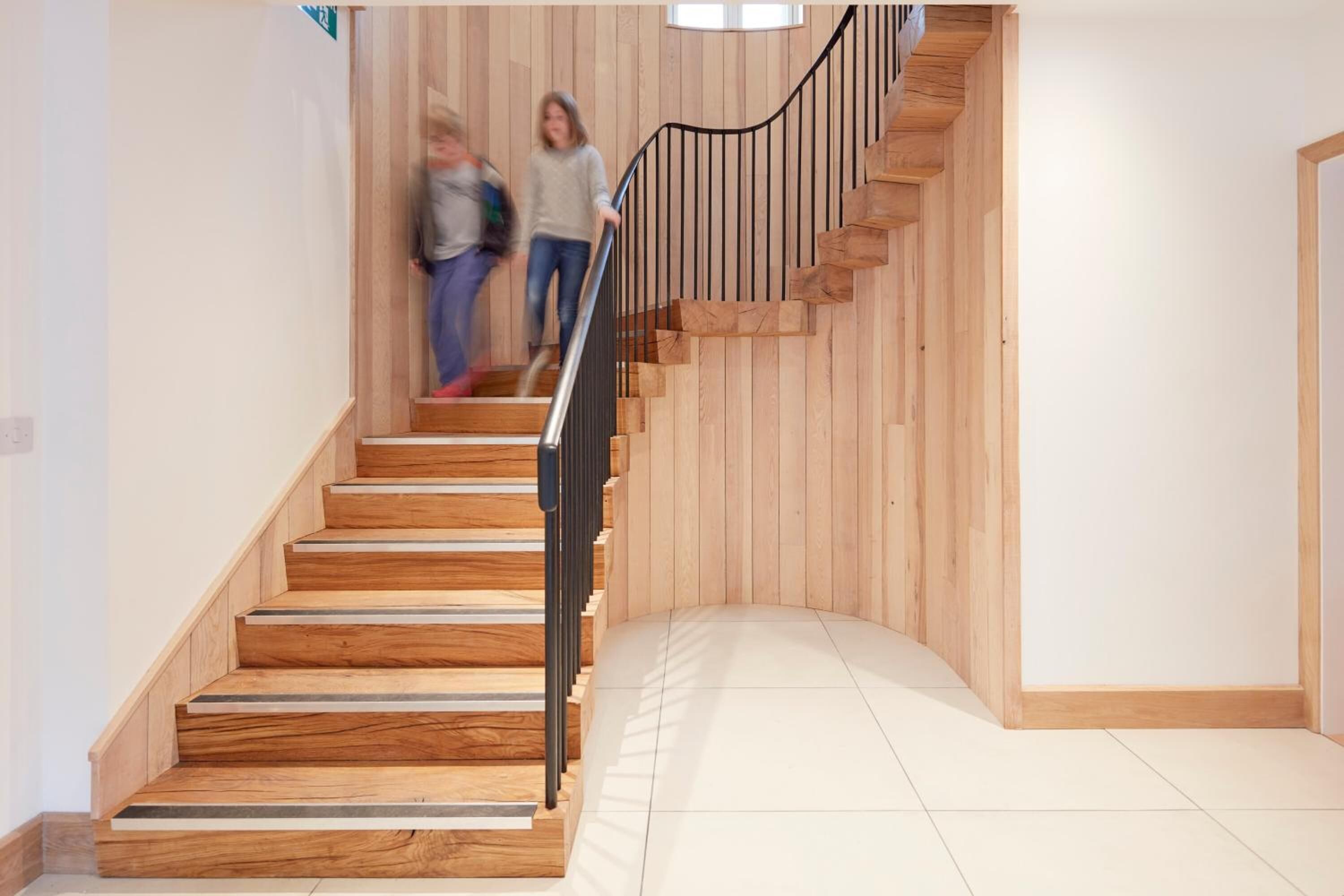 Un escalier en bois avec une rampe noire menant à un palier.
