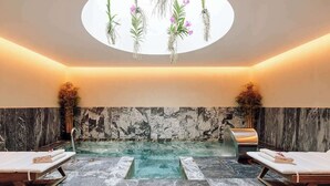 A spa room with a marble floor, a central water feature, and two lounge chairs. - The One Palácio da Anunciada (Lisbon)