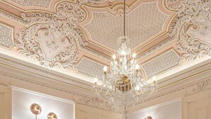 A luxurious dining area with ornate ceiling details, a chandelier, and modern lighting fixtures.
