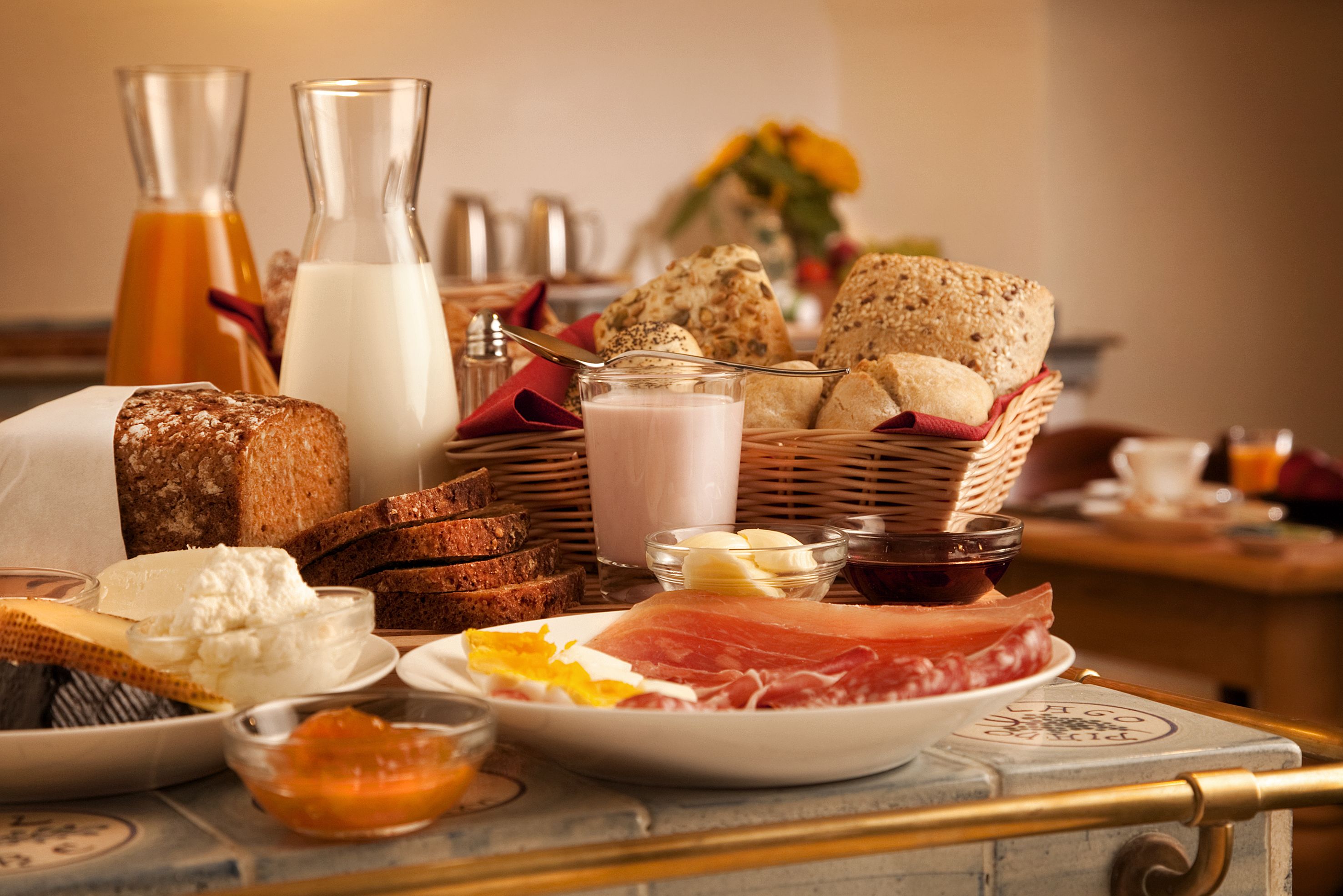 A breakfast table with bread, cheese, ham, and condiments.