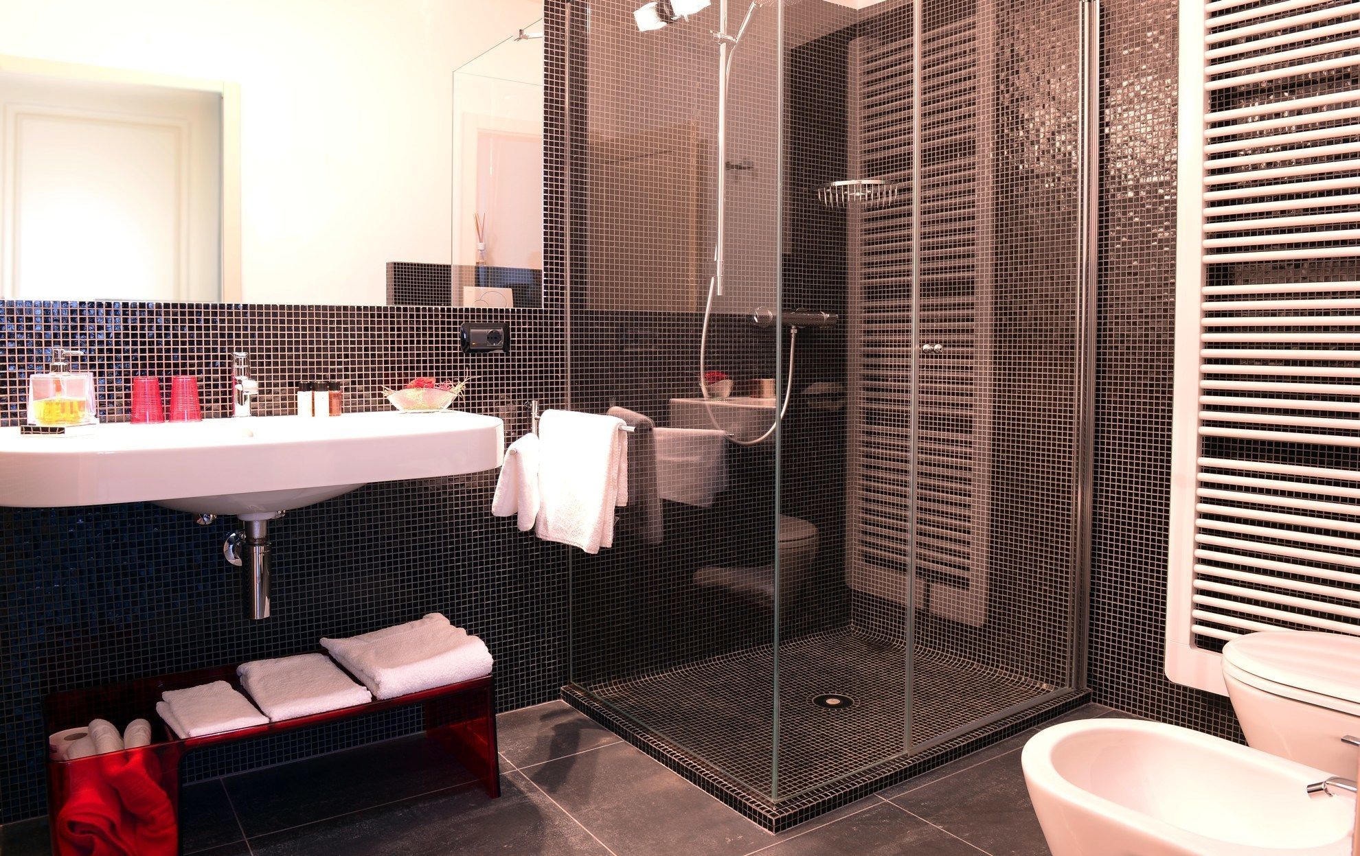 A modern bathroom with a glass-enclosed shower, a white sink, and a toilet.
