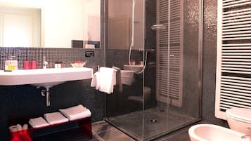 A modern bathroom with a glass-enclosed shower, a white sink, and a toilet.
