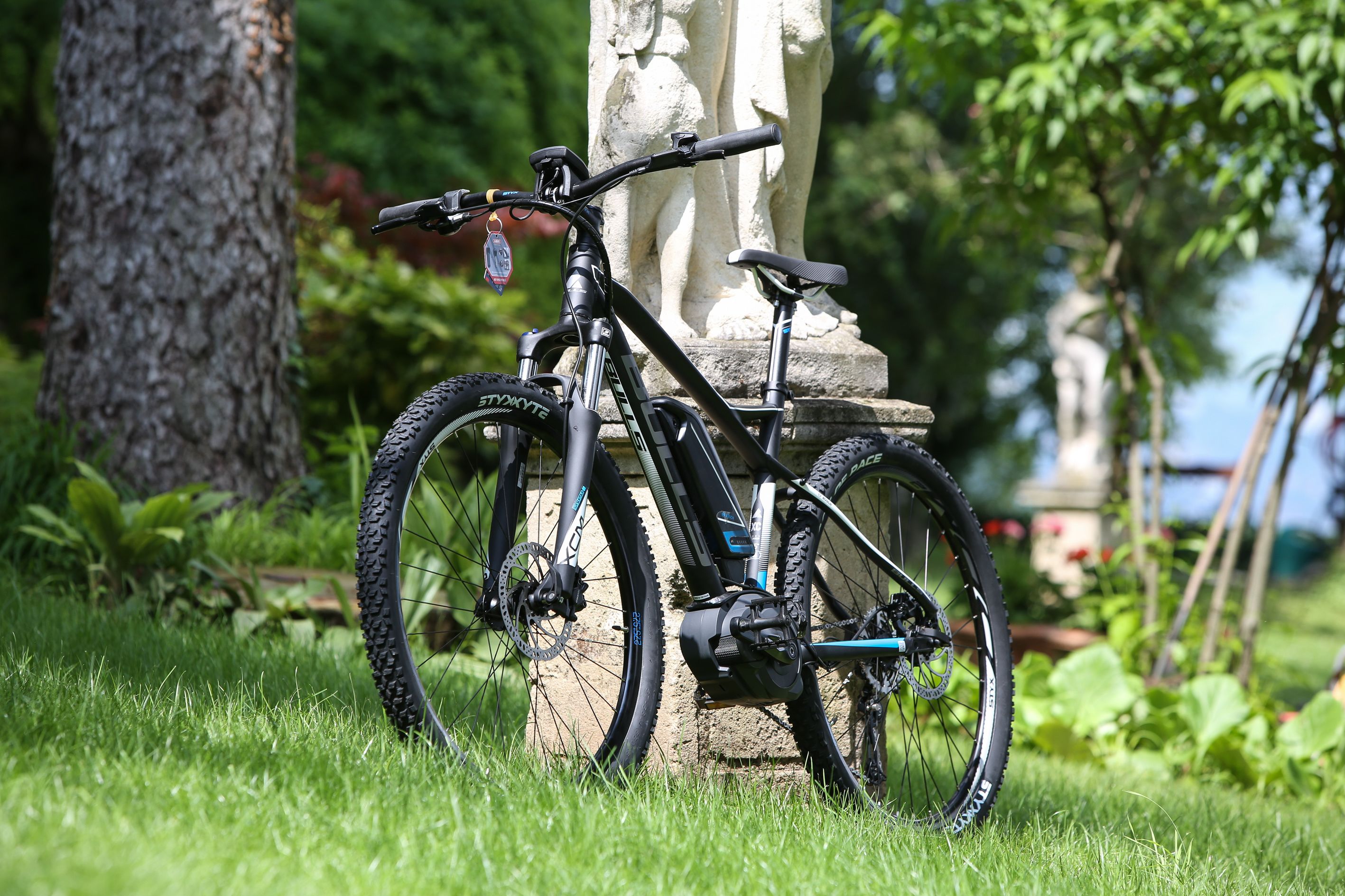 Uma bicicleta de montanha estacionada na grama perto de uma estátua de pedra.