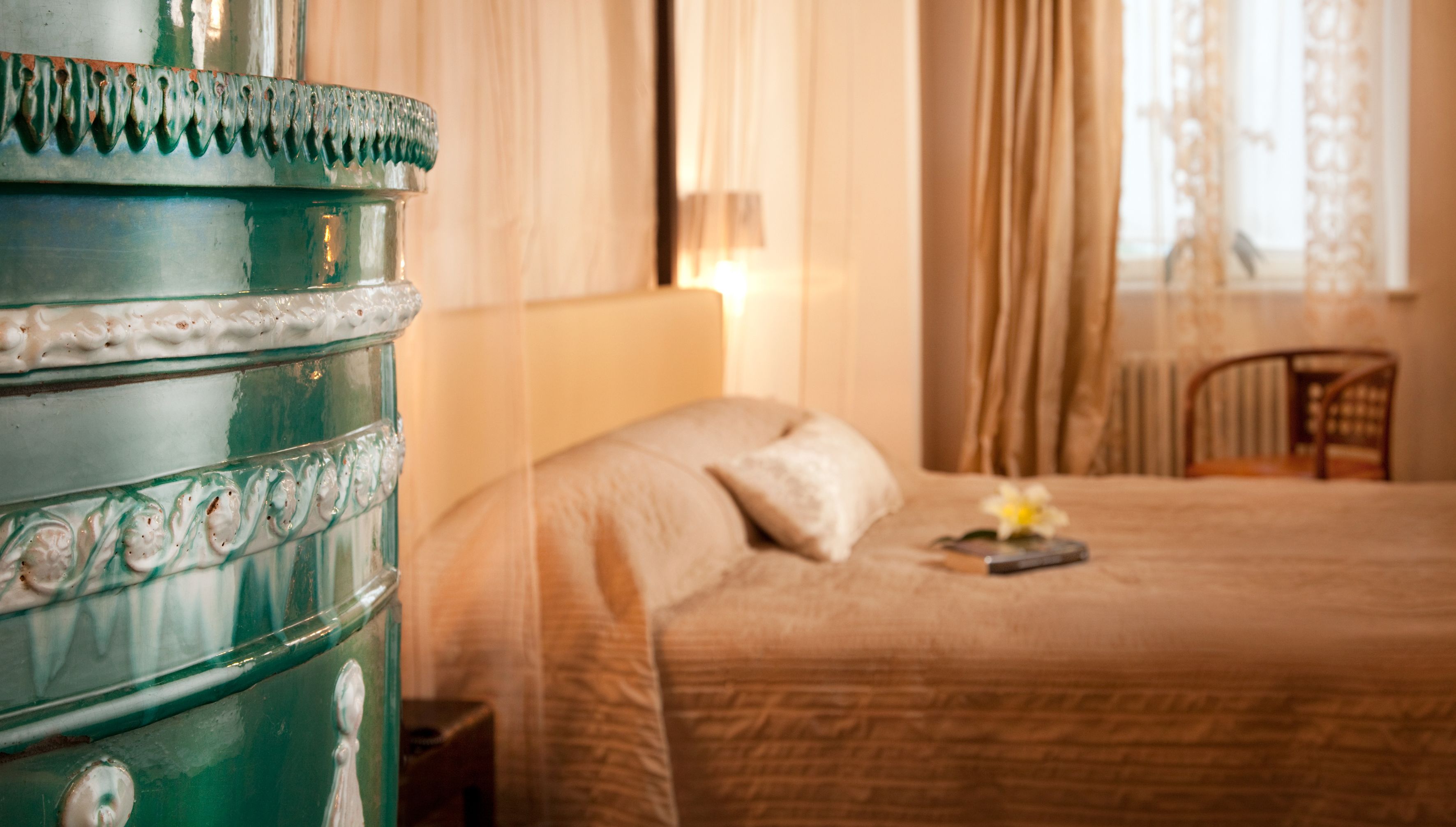 A bedroom with a large green dresser, a bed with a floral pillow, and a chair.