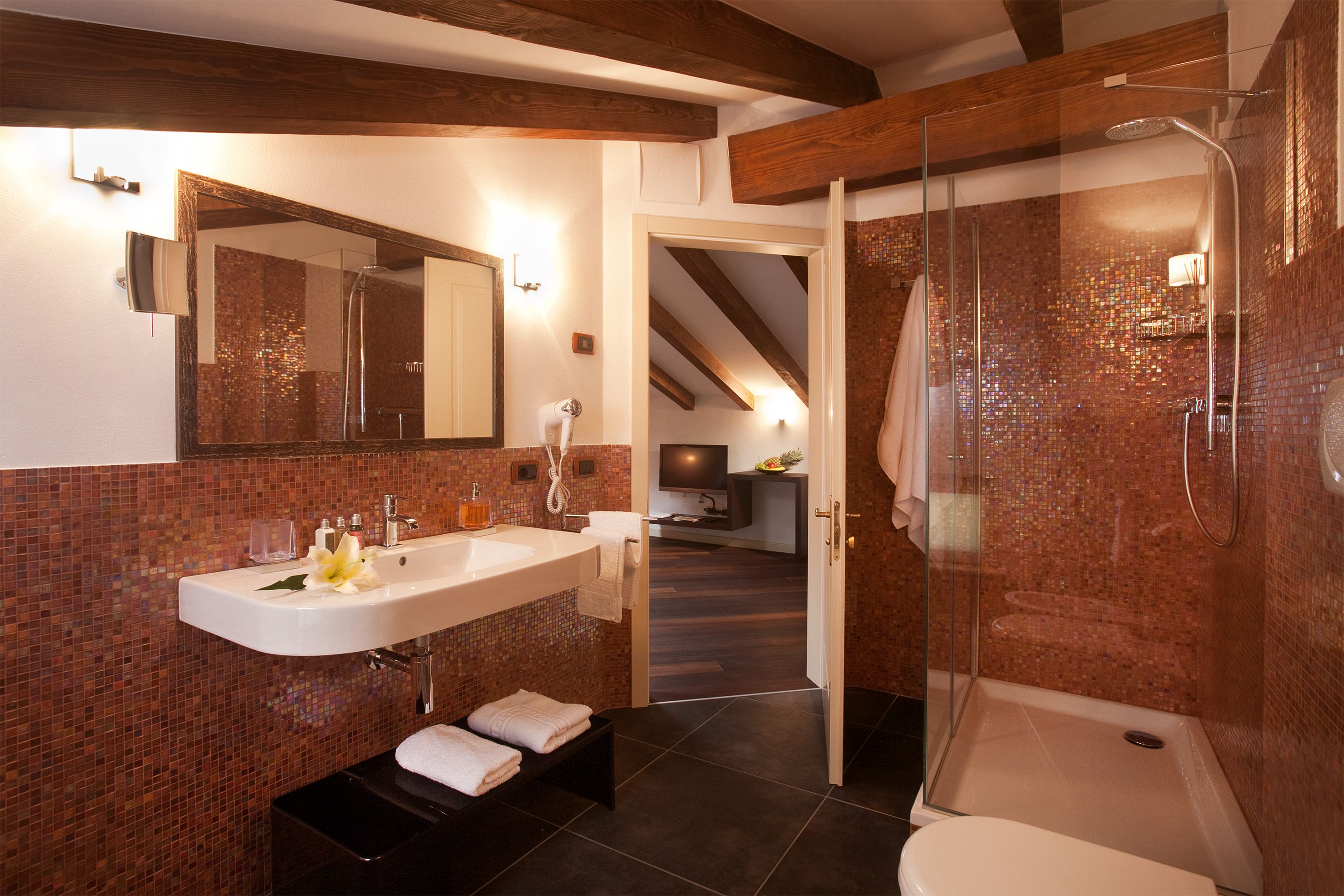 A modern bathroom with a glass-enclosed shower, a white sink, and a mirror above it.
