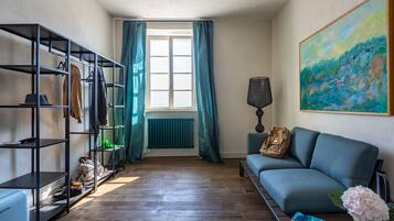 Ein Wohnzimmer mit Sofa, Heizkörper, einem Gemälde und einem Schuhregal.