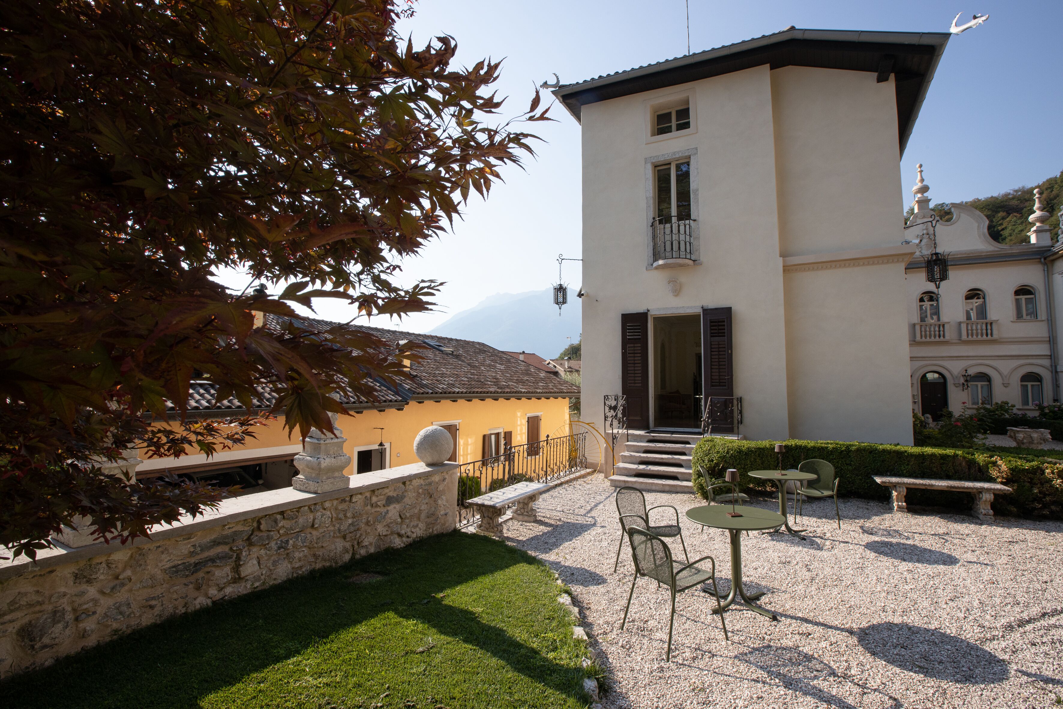 Ein Innenhof mit Steinmauer, einer Bank und einem Tisch mit Stühlen.